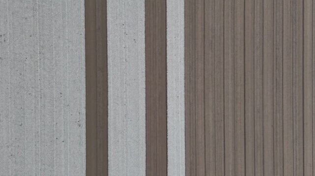 Parallel cultivated rows, contrasting soil textures, precise field alignment, prepared agricultural land, Po Valley farmland, geometric farming pattern, top down aerial view