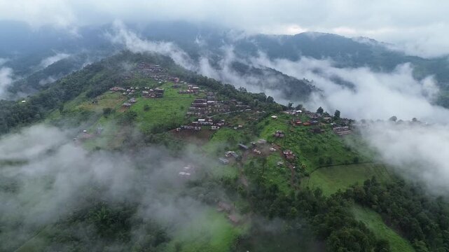 Misty Mountain Village Aerial Landscape with Green Hillside, Scattered Homes, Cloud Cover, Lush Forest, Remote Highland Valley, and Peaceful Rural Mountain Atmosphere