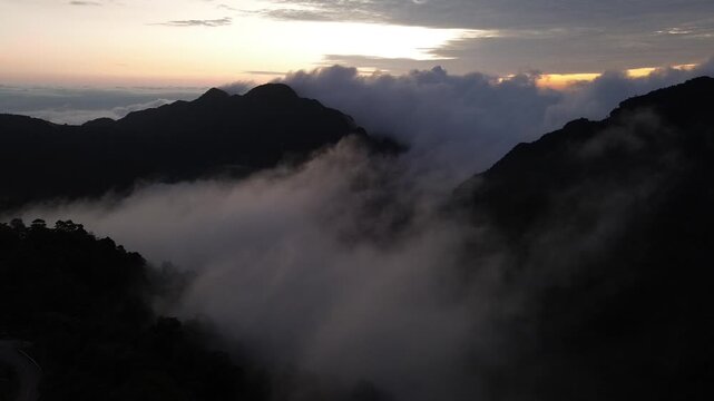 Mountain Ridge at Dawn, Misty Forest Valley, Dark Peak Silhouette, Rolling Cloud Cover, Glowing Sunrise Horizon, Dramatic Alpine Landscape, Tranquil Natural Scenery, Distant Mountain Peaks