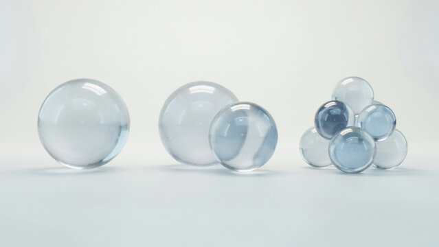 Collection of clear glass spheres and a cluster of orbs on a light background