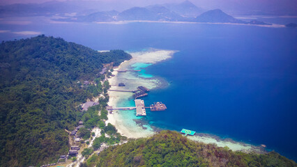 Aerial view of tropical island resort with jetties, helipad, and coral reefs in turquoise ocean © rhpermana