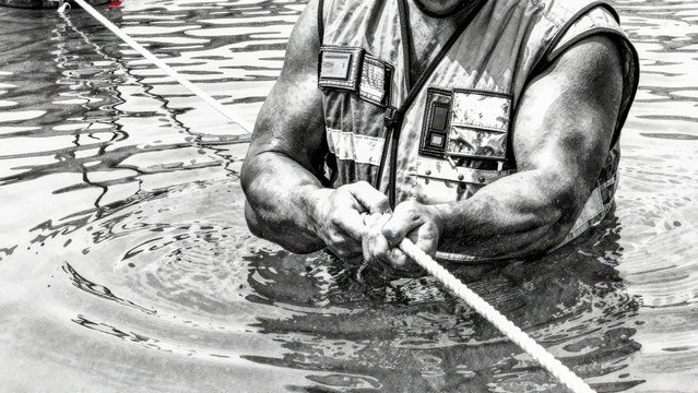 Strong Man Pulling Rope in Water in Safety Vest During Rescue Effort