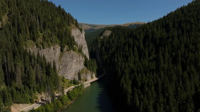 Drone reveal shot flying through the rocky Tatarului Gorge, opening up to a vast mountain valley and pine forests in Bucegi, Romania