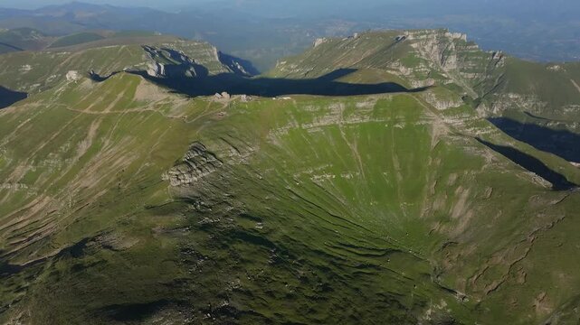High-altitude aerial drone shot showing the panoramic view of Omu peak and its alpine plateau in the Bucegi mountains of Romania.