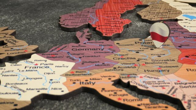 A close up view of a wooden european map with a small belarus flag icon slowly moving around on top of it.