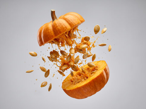 Ripe Orange Pumpkin Exploding In Halves With Seeds Flying Out