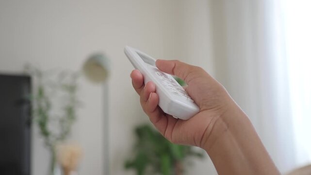 Person holding a air condition remote control in a living room setting during day
