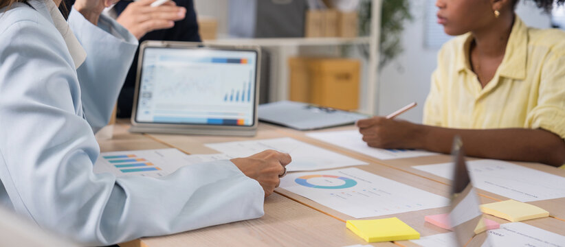Business team discussing financial charts and data on a digital tablet during a meeting in a modern office corporate strategy, and teamwork.