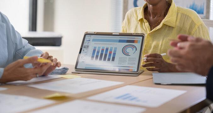 Business team discussing financial charts and data on a digital tablet during a meeting in a modern office corporate strategy, and teamwork.