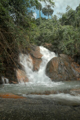 A waterfall cascading over rocky terrain, surrounded by lush greenery and dense vegetation. © k33pcalmncapture