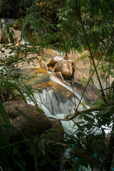 A flowing river or stream surrounded by lush greenery and large rocks. © k33pcalmncapture