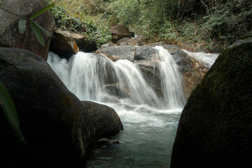 A serene waterfall cascading over smooth rocks, surrounded by lush greenery. The water flows softly, creating a tranquil atmosphere. © k33pcalmncapture