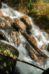 A flowing stream over smooth rocks, surrounded by lush greenery. Water cascades gently down the stones, creating a serene and natural atmosphere. © k33pcalmncapture