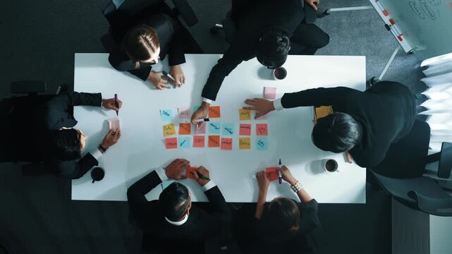 Top down aerial view of skilled diverse business group choosing marketing strategy while businessman standing and presenting project by using mind map at meeting room. Teamwork concept. Directorate.