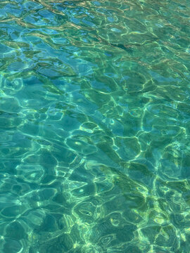 Sea emerald green crystal clear water with sun reflections vertical 