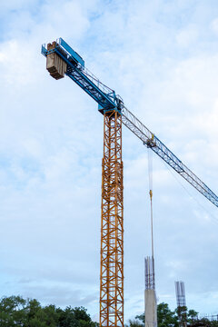 Tall crane tower stands at construction site, operating heavy machinery for building project. Powerful industry steel equipment reaching blue sky evokes confident, hopeful progress