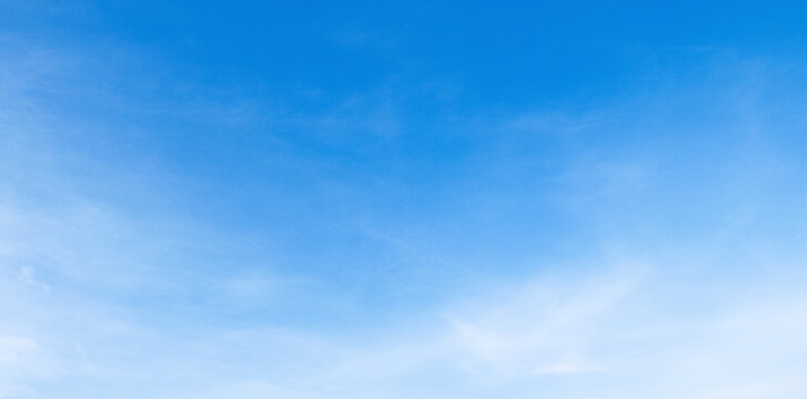 Clear blue sky with soft, wispy clouds drifting