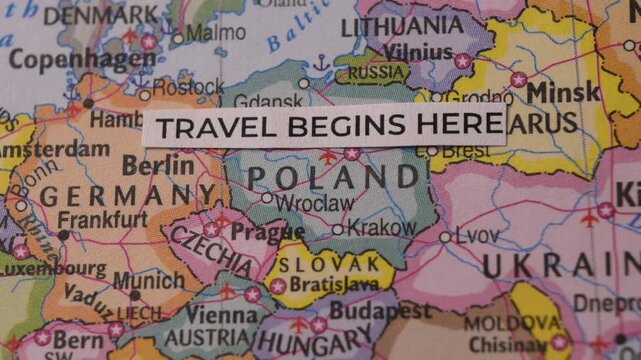Paper strip with Travel Begins Here text on a map of Europe