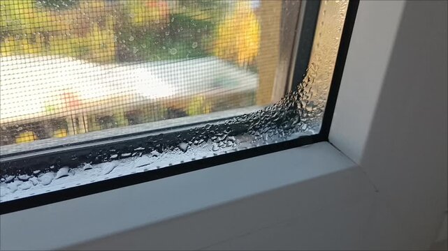 Water condensation on plastic window frame corner, bad insulation and cold glass problem indoor horizontal view. 
