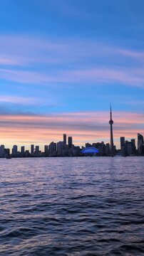 Evening in Toronto with a beautiful blue sky&mdash;downtown skyline and a calm lake. View from the island. Vertical video, pan shot. Toronto, Ontario, Canada