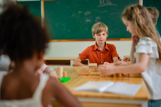 School children work together on classroom learning activity with teacher nearby, developing creativity, communication, teamwork and problem solving through collaborative educational play.