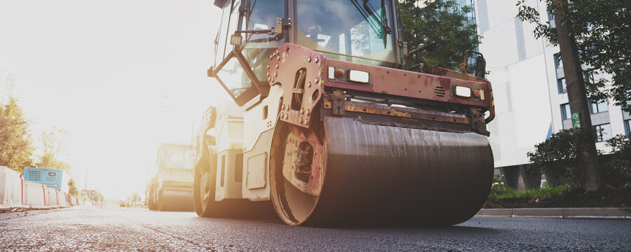 Road Roller Compacts Fresh Asphalt on a Sunny City Street During Urban Paving Works