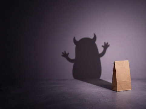 Brown paper grocery bag casting a spooky monster shadow on the wall