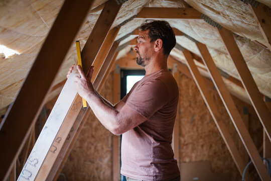 Homeowner doing DIY renovation work in unfinished attic.