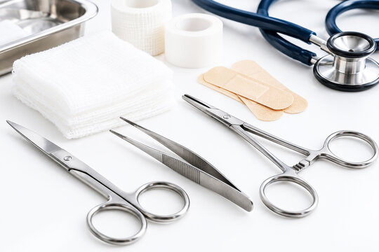 Medical instruments, gauze and adhesive bandages arranged on a clinical work surface. Stethoscope and surgical tools for examination and wound care. Healthcare, first aid and medical
