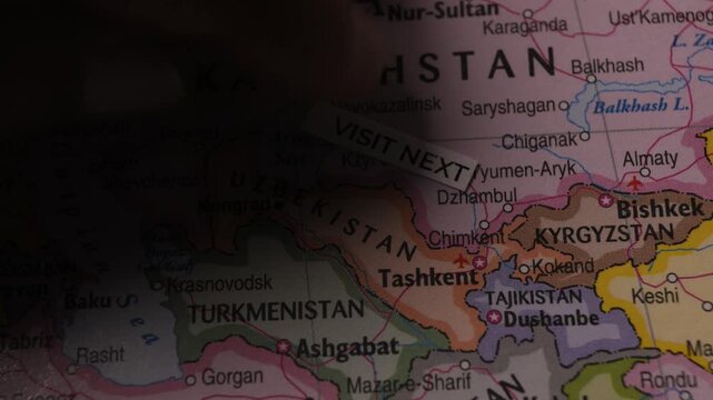 Paper tag with text Visit Next placed on Uzbekistan map for travel planning