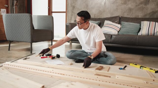 Asian mature man preparing flat-pack furniture parts and DIY equipment for self-assembly with instruction manual, home improvement, wooden craft install hobby workshop, handyman active lifestyle.