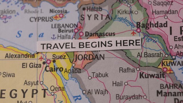Paper strip with text Travel Begins Here placed on Middle East map
