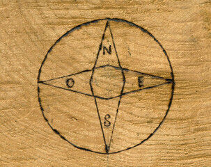 Hand-burned compass rose pyrography on wood with Italian cardinal letters N E S O. Warm grain texture and rustic artisan craftsmanship for navigation, travel, and vintage map themes. © Grenar