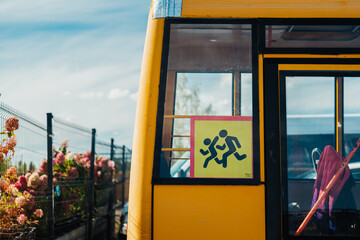 Yellow school bus with child crossing sign near fenced garden © reddish