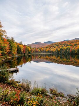 Serene Autumn Lake Reflection with Colorful Trees and Mountains.
