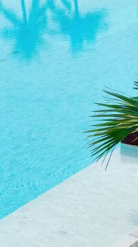  Vertical view of clear blue water and white tile edge of luxury swimming pool at modern resort.