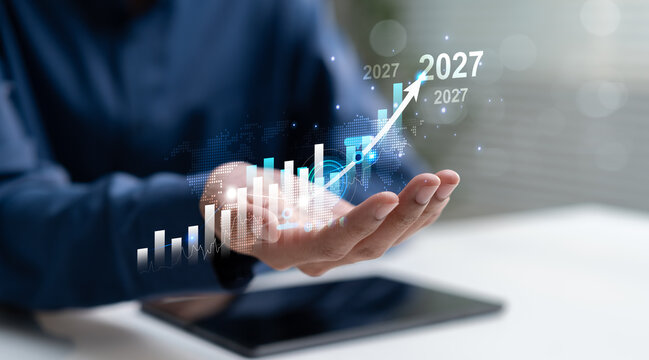 Businessman presents a rising digital chart with 2027 forecast, representing financial growth, market performance, investment strategy, economic outlook and future business success.