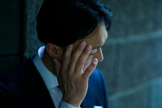 顔に手を当ててうつむく男性ビジネスマン