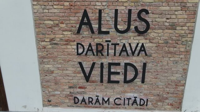 Close up of a Latvian welcome sign reading brewery viedi displayed on a textured brick wall