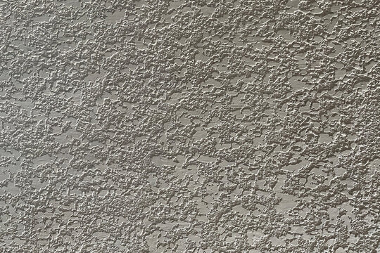 Light gray rough plaster wall texture with irregular raised patterns and natural surface variation,