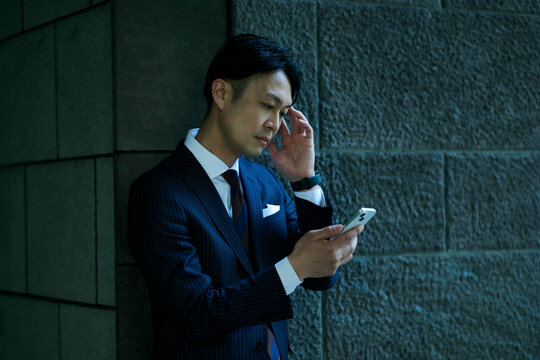 スマートフォンを見て頭を抱える男性ビジネスマン