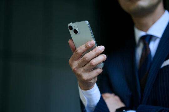 スマートフォンを持つビジネスマンの手元のクローズアップ