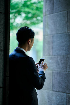 スマートフォンを見る男性ビジネスマンの後ろ姿