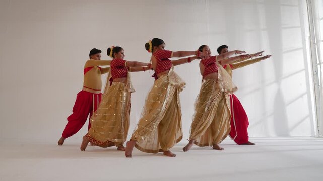A group of dancers  performing a traditional Indian routine in a studio setting