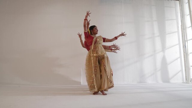 Indian classical dancers performing synchron ed movements indoors