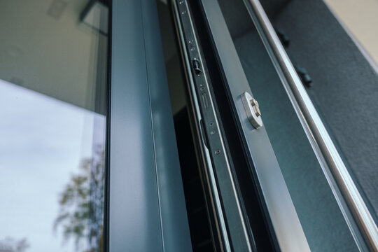 Modern dark gray aluminum front door open with visible security lock system and handle