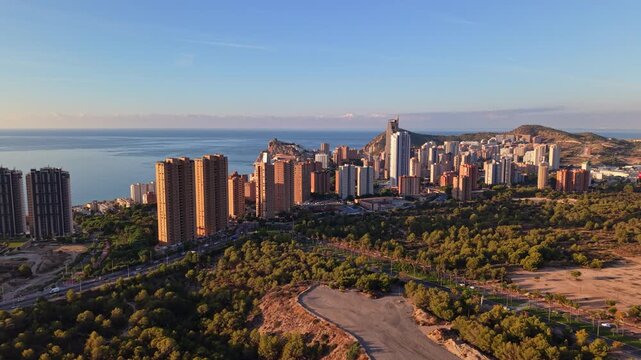 The skyline of Benidorm with tall buildings and views of the coastline. The area is vibrant and set beside the sea during the daytime.