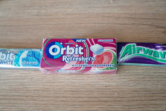 Assorted packs of Wrigley's chewing gum including Orbit Refreshers and Airwaves on a wooden table