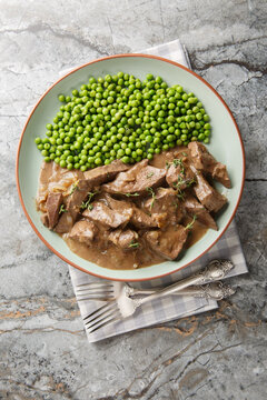Baden style Saure Leber sour liver with green peas garnish close-up in a plate on the table. Vertical top view from above