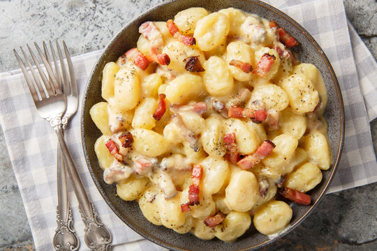 creamy gnocchi carbonara with a rich savory sauce made from eggs, cheese and pancetta closeup on the plate on the table. Horizontal top view from above